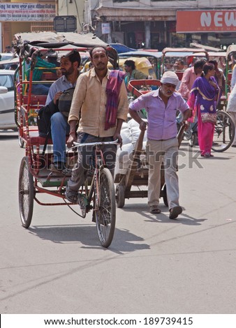 DELHI, INDIA - MARCH 28, 2014: A cycle rickshaw transports a passenger through the Chandni Chowk bazaar area in the centre of Delhi. This type of vehicle is extensively used in congested Indian cities