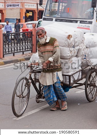 JAIPUR, INDIA - MARCH 26, 2014: Heavy load being towed by a porter through the heart of the city. The use of porters to transport goods consignments in this way is common in Indian towns and cities