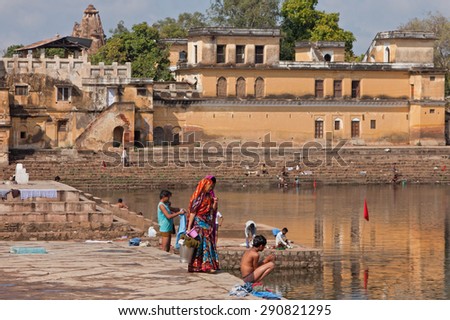 KHAJURAHO, INDIA - MARCH 2, 2015: Towns people bathing themselves and washing clothing at the principal ghat giving access to Shiv Sagar lake. Many locals do not have access to a domestic water supply