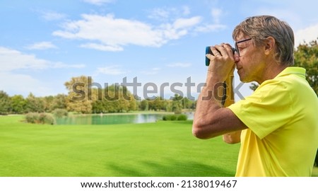 The golfer accurately measures the distance to the flag in a golf course with the laser rangefinder. In the background the forest. Сток-фото © 