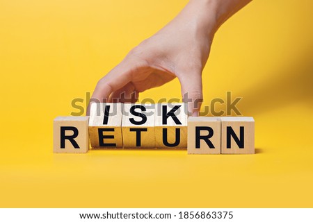 Hand flipping wooden blocks for wording RISK RETURN. Risk management and risk tolerance concept.