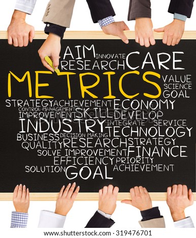 Photo of business hands holding blackboard and writing METRICS word cloud