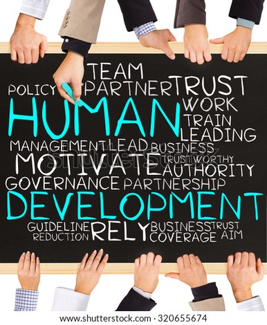 Photo of business hands holding blackboard and writing HUMAN DEVELOPMENT word cloud