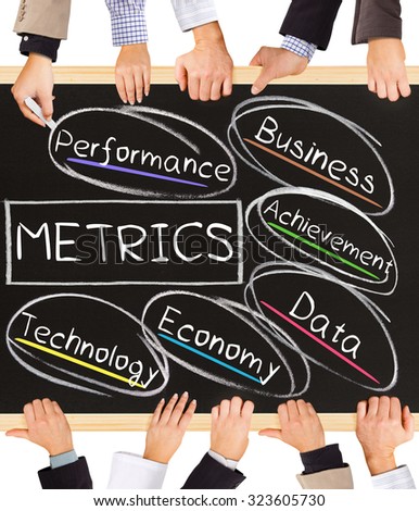 Photo of business hands holding blackboard and writing METRICS diagram