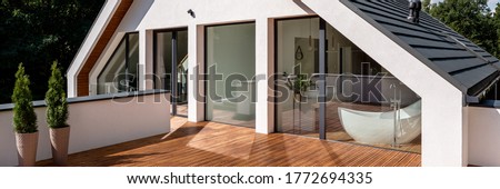 Panorama of elegant house balcony with wooden floor and with entrance from balcony window in attic bathroom with bathtub