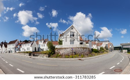 STAVANGER, NORWAY - JULY 23: View to the traditional Norwegian white wooden houses and a pair of tourists in the background, on July 23, 2015 in Stavanger, Norway.