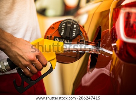 Hand refilling the car with fuel, close-up.