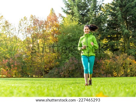 Young happy brunette woman training outside during autumn day and listening to music.