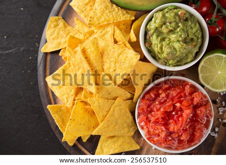 Green Guacamole with nachos and avocado on stone background