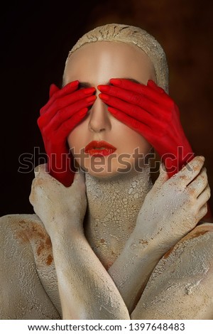 girl covered with clay with cracks and holds red hands that close her eyes Stock foto © 