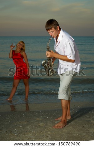man with  saxophone music for the beloved woman on the beach