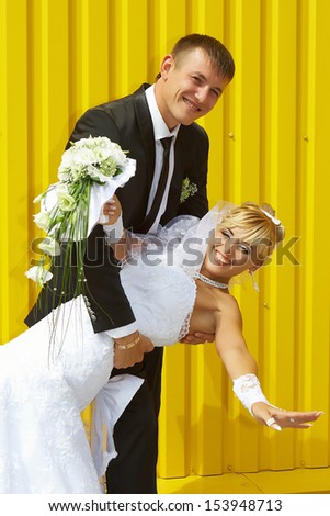 funny bride and groom yellow background laughing and having fun