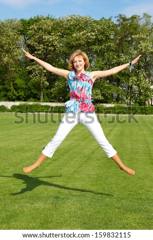 Happy positive blond woman jump on grass sunny day