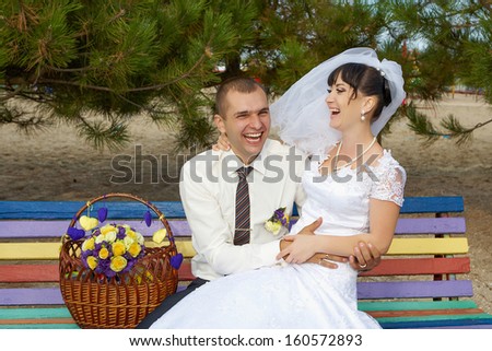 funny bride and groom sit on the bench laughing and having fun