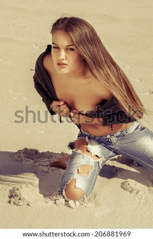 beautiful hot girl in ripped jeans and a leather jacket in the desert