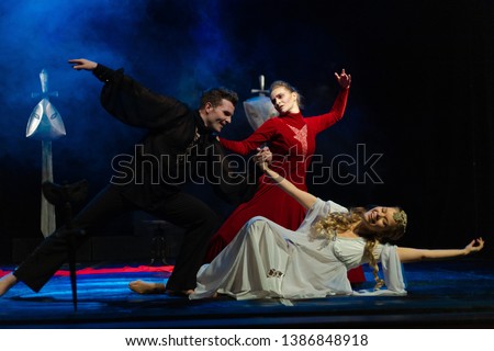 Actors and actresses in red, white and black suits, on the theater stage show a dramatic performance.