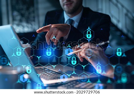 Two colleagues working together to protect clients confidential information and cyber security. IT hologram padlock icons modern office background at night time Foto stock © 