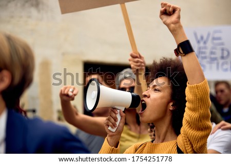Young African American woman with raised fist shouting through megaphone while being on anti-racism protest.  Stock foto © 