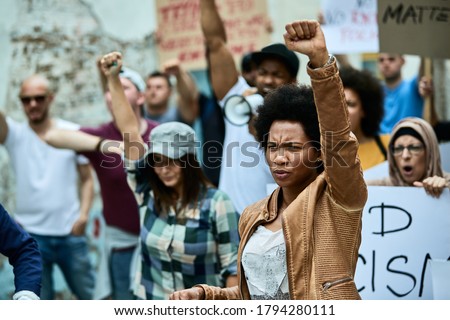 African American woman with raised fist participating in black civil rights demonstrations. 