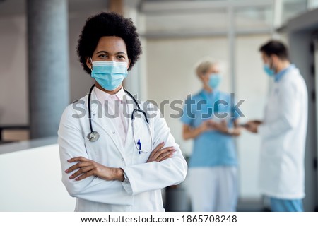 Confident African American female doctor wearing protective face mask while standing with arms crossed in a hallway at the hospital.  ストックフォト © 