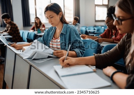 Similar – Image, Stock Photo Student learning in university library. Young woman writing essay and making notes using computer tablet. Focused student studying for college exams