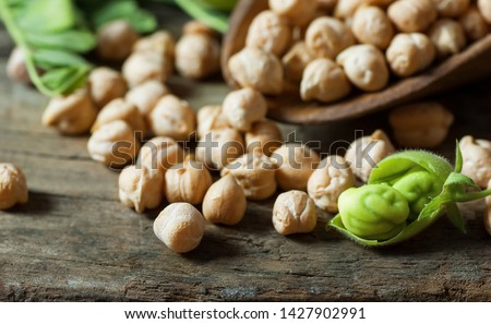 Uncooked dried chickpeas in wooden spoon with raw green chickpea pod plant on wooden table. Heap of legume chickpea background Stockfoto © 