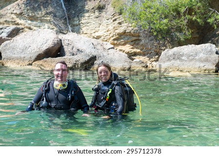 Two divers standing with their equipment standing in shallow water before a dive