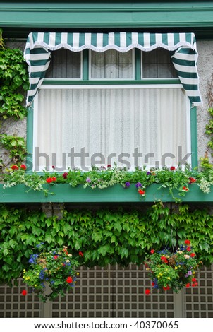 Beautiful vintage building window with flowers in the historic butchart gardens (over 100 years in bloom), vancouver island, british columbia, canada