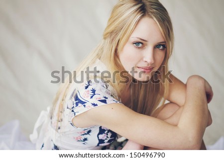 Beautiful young blonde girl dreamy-looking is sitting on the floor