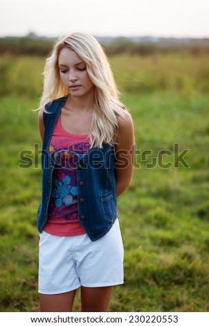 Beautiful young girl walks alone in a field