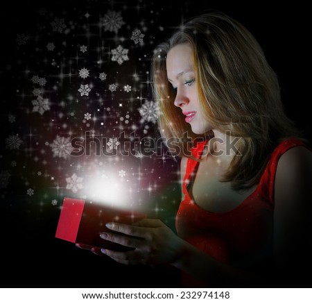woman smiles and holding a gift in magic packing on a black background