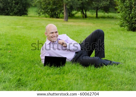 man with laptop lying on green grass in the park