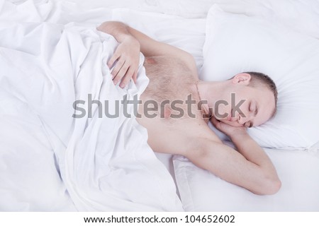 handsome young man is sleeping in bed with white linen