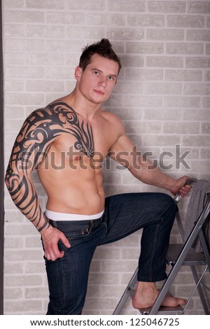 Muscular Sexy Man with tattoo posing near the ladder