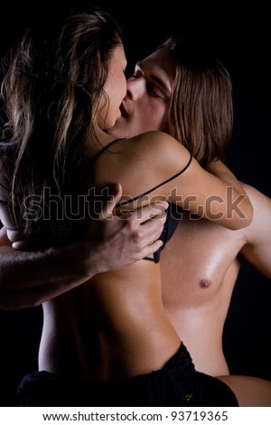 A young man with long hair and a muscular back passionately engaged in sex with a beautiful girl at the wall