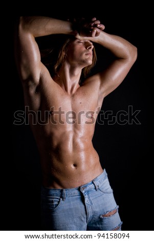 young guy with long hair, naked and wet with a muscular torso against a dark background