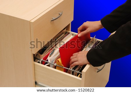Filing Cabinet - woman putting back an important file into cabinet