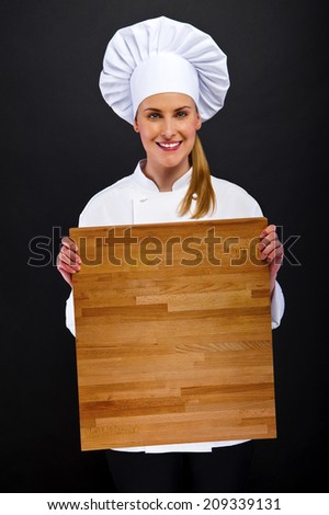 woman chef holding wooden board pointing with smile