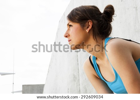 young woman resting after run by the wall in city with big smile. in blue sportswear.