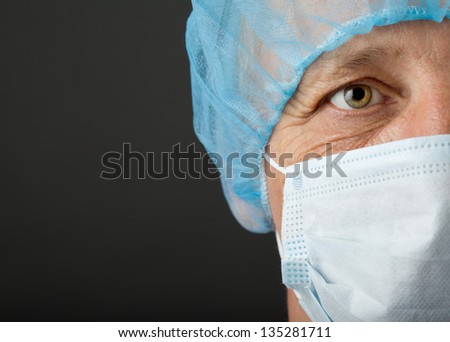 Doctor\'s face with mask and cap on grey background