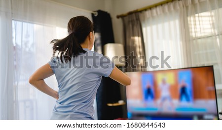 Fitness online Stay home.home fitness workout class live streaming online.Asian woman doing strength training cardio aerobic run exercises.Watching videos on a smart tv in the living room at home.