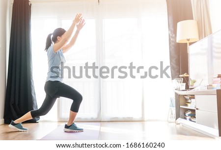 Video streaming Stay home.home fitness workout class live streaming online.Asian woman doing strength training cardio aerobic dance exercises watching videos on a smart tv in the living room at home.