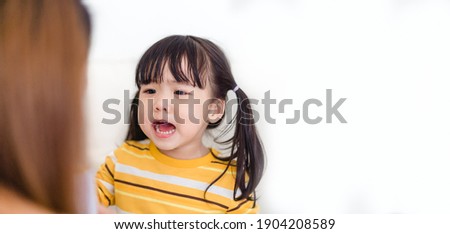 Angry asian kid.Little asian girl looking at her mother and fighting with her mom.Furious hungry toddler kid got upset and sad.Stubborn child bad attitude.Depressed little girl complaining with mom.