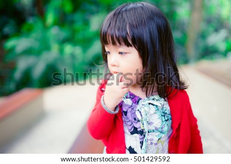 Little asian girl sucking thumb in crib and looking. Closeup portrait of fun little girl.
 商業照片 © 