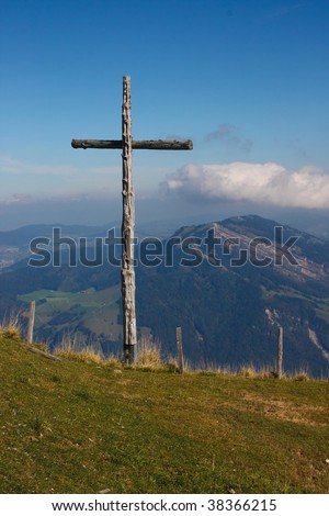 thats the big cross on Rigi mountain, Switzerland. In the background are the Alps, connected with the blue sky with some clouds.