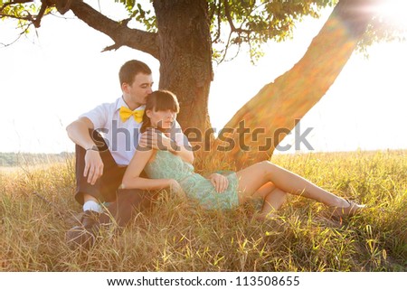 Young couple lying under the tree with backlight