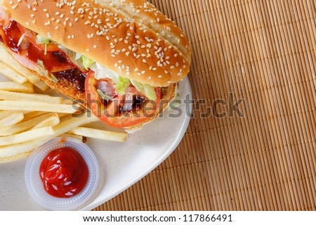 Burger with fries and tomato ketchup on bamboo mat
