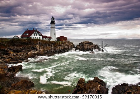 Portland Head Lighthouse sits on the edge of the Atlantic Ocean while the waves crash on the rocky coast
