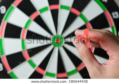 Hand aims a dart as ready to throw it at the target
