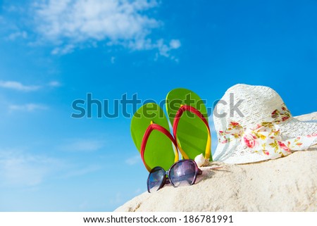 Green flip flop, sunglasses and floppy hat at the beach